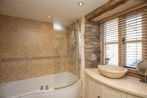 a bathroom with a bath tub and a sink at Penny Red Cottage in Ambleside