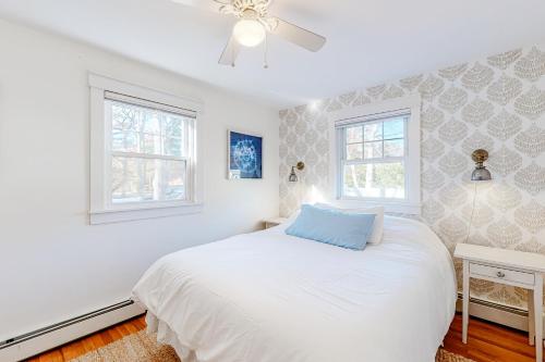 a white bedroom with a bed and two windows at Childs River Hollow in East Falmouth