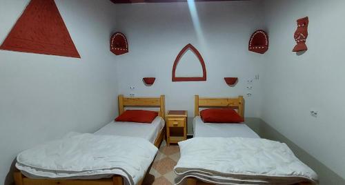 two beds in a room with a wall with a window at Dar Agham Akbou in Timimoun