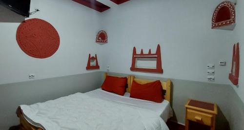 a bedroom with a bed with red pillows on it at Dar Agham Akbou in Timimoun