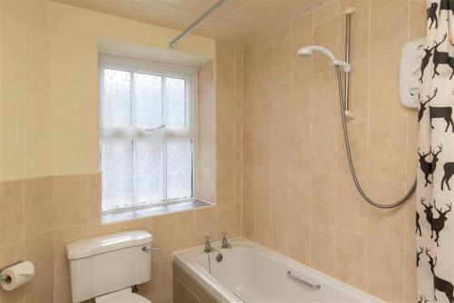 ein Badezimmer mit Badewanne, Toilette und Dusche in der Unterkunft Sunset Cottage in Ambleside