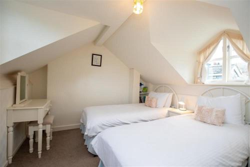 Zimmer im Dachgeschoss mit 2 Betten, einem Schreibtisch und einem Waschbecken in der Unterkunft Sunset Cottage in Ambleside