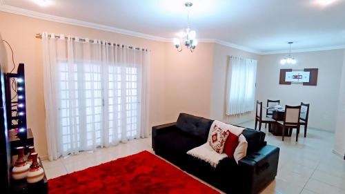a living room with a black couch and a red rug at Casa Confortável, 3 Quartos, Ar Condic. 300 Mega, Taubaté in Taubaté