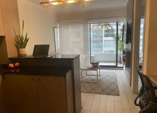 a living room with a laptop computer on a counter at Departamento en Ñuñoa, excelente ubicación, frente metro y a pasos del barrio italia in Santiago