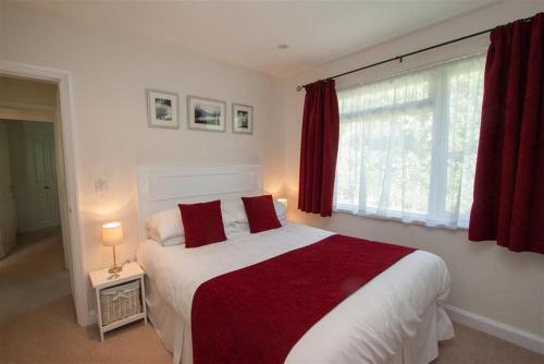 a bedroom with a large bed with red sheets and a window at Bield How in Ambleside