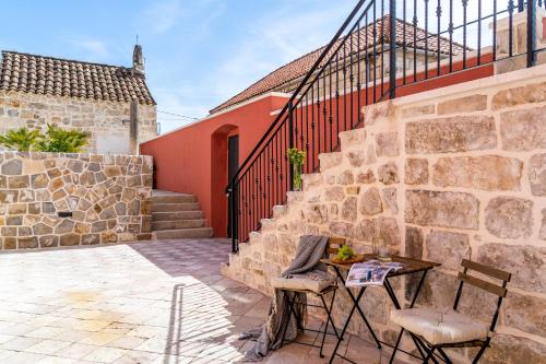 a patio with a table and chairs next to a stone wall at Cavtat Old School in Cavtat