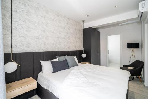 a bedroom with a large white bed and a chair at Cavtat Old School in Cavtat