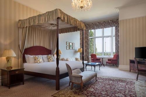 um quarto com uma cama de dossel e uma sala de estar em The Welcombe Golf & Spa Hotel em Stratford-upon-Avon