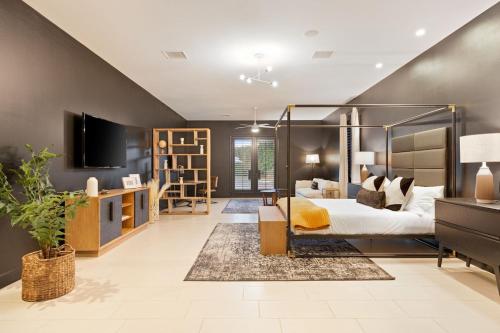 a bedroom with a canopy bed and a tv at Santal Estate - Play, Relax, Walk to the Festivals in Indio