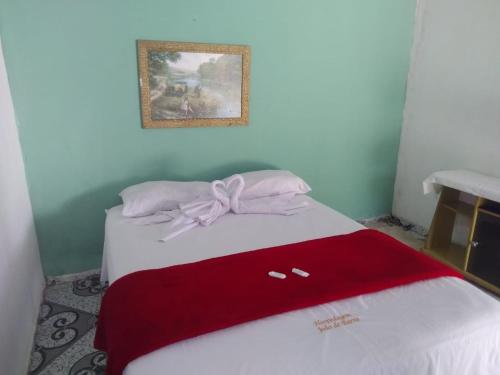a bed with a red blanket with a bow on it at João de Barro Hospedagem in Caeté-Açu