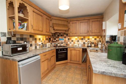 a kitchen with wooden cabinets and a counter top at Bleaberry Cottage in Penrith