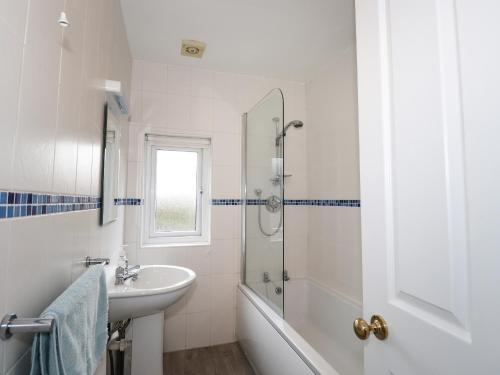 a white bathroom with a sink and a shower at Larch Cottage in Ambleside