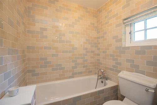 a bathroom with a white tub and a toilet at Crozier Cottage in Ambleside