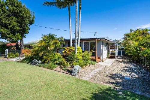 a house with palm trees and a yard at Fins Hideaway in Iluka