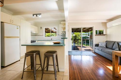 a kitchen and living room with a counter and stools at Fins Hideaway in Iluka