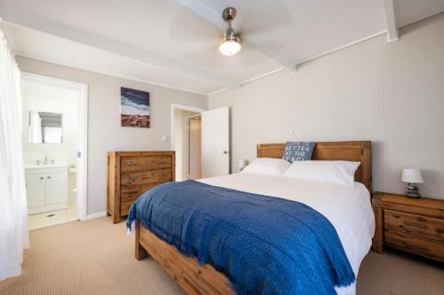 een slaapkamer met een groot bed en een blauwe deken bij Fins Hideaway in Iluka