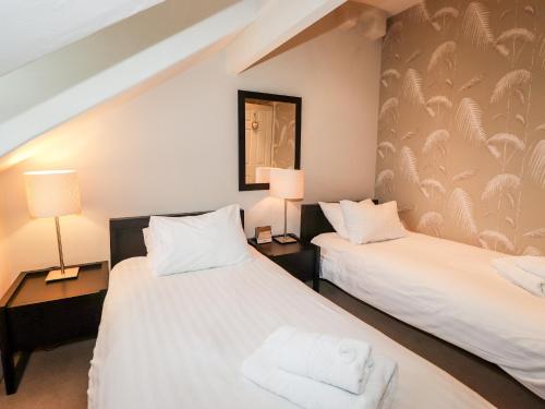 duas camas num quarto com dois candeeiros e toalhas em Hazeldene em Ambleside