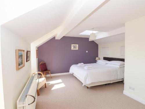 a bedroom with two beds and a purple wall at Robin Cottage in Troutbeck