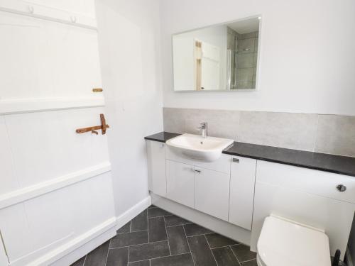 a white bathroom with a sink and a toilet at Robin Cottage in Troutbeck