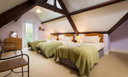 a bedroom with three beds with green blankets at Hawkshead Hall in Hawkshead