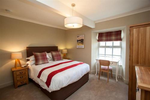 a bedroom with a bed and a table and a window at Swallow's Nest in Bowness-on-Windermere