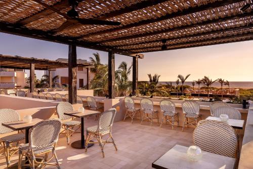 a patio with tables and chairs and the ocean at Kimpton Mas Olas Resort and Spa in Todos Santos