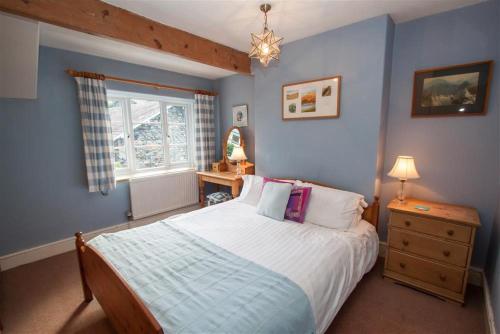 a blue bedroom with a bed and a window at Briardale Cottage in Ambleside