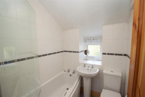 a white bathroom with a sink and a tub and a toilet at Briardale Cottage in Ambleside