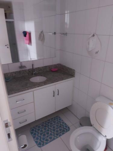 a bathroom with a toilet and a sink and a mirror at Apartamento em guarajuba 200m da praia in Camaçari