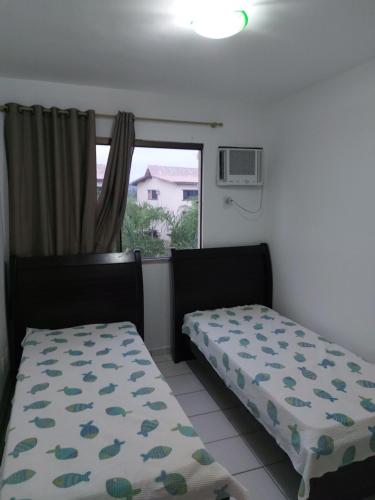 Apartamento em guarajuba 200m da praia في كامساري: سريرين في غرفة مع نافذة