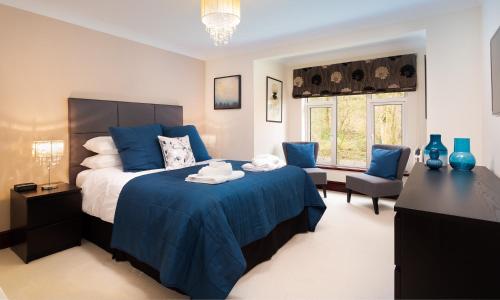 1 dormitorio con 1 cama azul y sillas azules en Beech View, en Ambleside