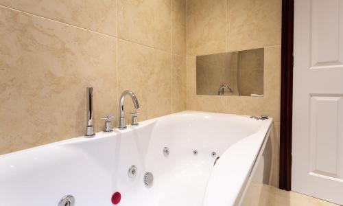 baño con bañera blanca y espejo en Beech View, en Ambleside