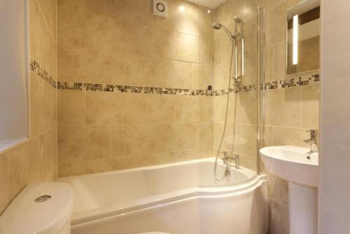 uma casa de banho com uma banheira, um WC e um lavatório. em Wythebank em Ambleside