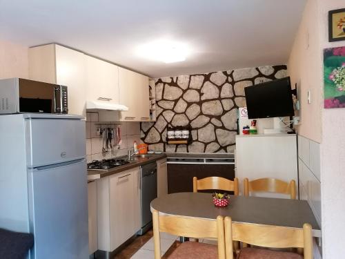 una pequeña cocina con mesa, sillas y nevera. en Apartment Njivice 5320b en Njivice