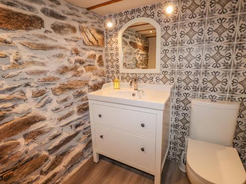 Glen View Cottage في آمبيلسايد: حمام مع حوض أبيض وجدار حجري