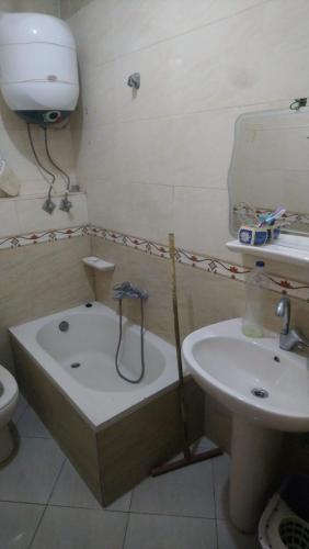 uma casa de banho com uma banheira ao lado de um lavatório em الهرم no Cairo