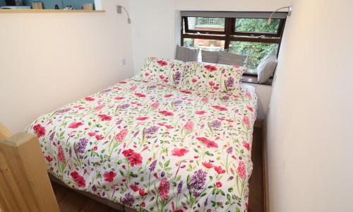 1 dormitorio con 1 cama con colcha de flores y ventana en Old Sawrey Stores, en Far Sawrey