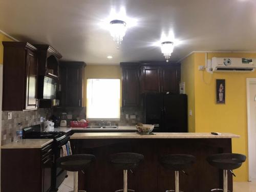 a kitchen with wooden cabinets and a counter with bar stools at palmvillo master suit in Gommier