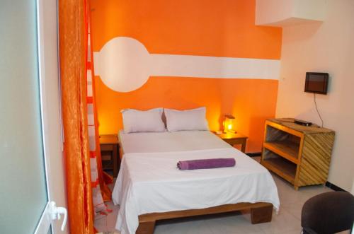 a bedroom with a bed with an orange wall at Kër Adja in Ziguinchor