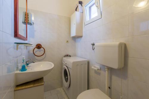 a white bathroom with a toilet and a sink at Apartment Karigador 2534b in Karigador