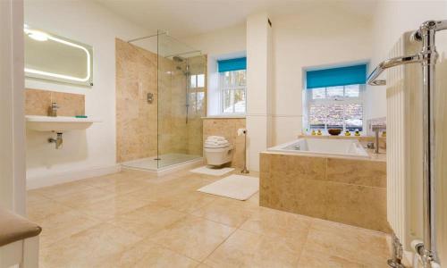 een badkamer met een douche, een bad en een toilet bij High Cleabarrow in Windermere