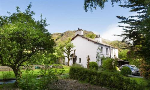 a white house with a hill in the background at Rose Cottage Coniston in Coniston