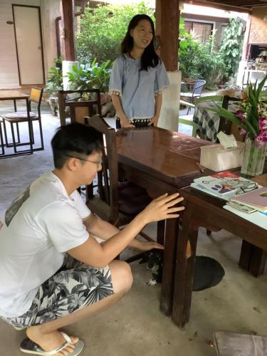 a man and a woman sitting at a wooden table at Baan Songjum in Chiang Mai