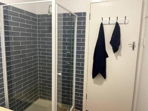 uma casa de banho com um chuveiro e uma porta de vidro em Beach House 100ms to Beach Freshly Renovated All New Appliances em Gold Coast