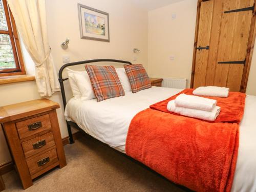 1 dormitorio con 1 cama con 2 toallas en Rum Bush Cottage, en Keisley