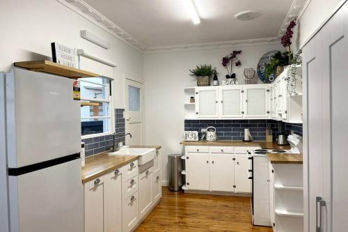 a kitchen with white cabinets and a white refrigerator at Beach House 100ms to Beach Freshly Renovated All New Appliances in Gold Coast