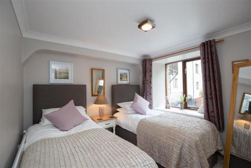 a bedroom with two beds and a window at Over Ghyll in Ambleside