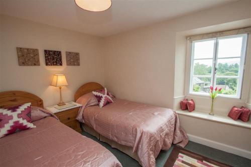 a bedroom with two beds and a window at Honeypot Cottage in Ambleside