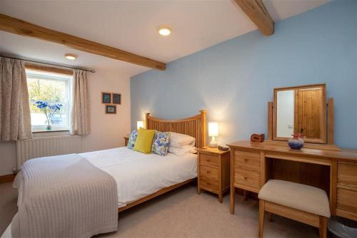 een slaapkamer met een bed, een dressoir en een spiegel bij Cygnet Cottage in Keswick