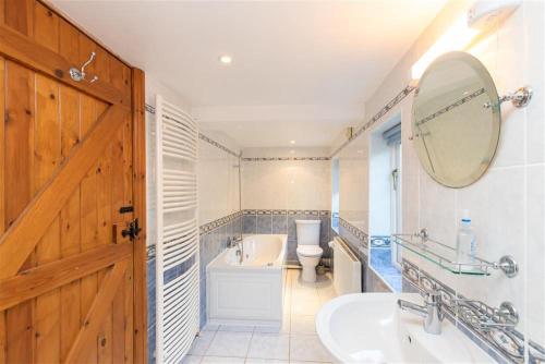 een badkamer met een wastafel, een toilet en een spiegel bij Cygnet Cottage in Keswick